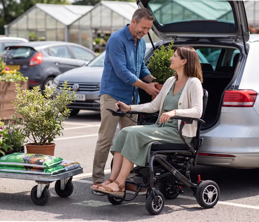 Woman using Monarch MM60 lightweight folding electric wheelchair beside an open vehicle